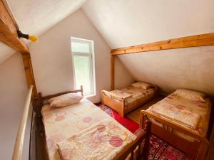 Zimmer im Dachgeschoss mit 2 Betten und einem Fenster in der Unterkunft Villat Bardhoshi in Mitrovica