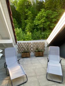 2 chaises blanches assises sur une terrasse couverte avec des arbres dans l'établissement Holiday Deluxe Apartment, à Travers