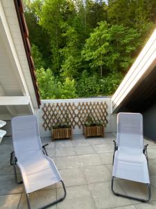 two white chairs sitting on a porch with trees at Holiday Deluxe Apartment in Travers