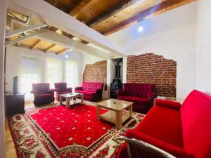 a living room with red chairs and a brick wall at Villat Bardhoshi in Mitrovicë