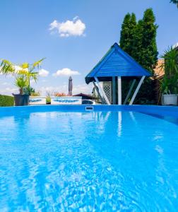 a blue swimming pool with a blue roof at Elena Apartaments in Sármellék