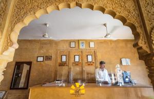 Ein Mann, der an einer Theke in einem Zimmer sitzt. in der Unterkunft Golden Haveli in Jaisalmer