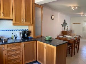 a kitchen with wooden cabinets and a dining room at Best Houses 78 - Casa Limão in Ferrel
