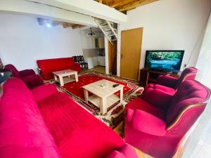 a living room with red couches and a tv at Villat Bardhoshi in Mitrovicë