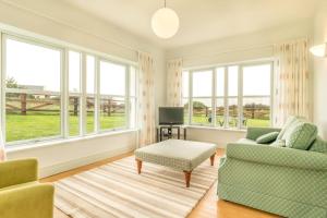 a living room with two chairs and a tv and windows at Country Setting in the Middle of Dingle Town. in Dingle