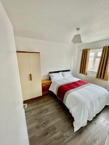 a white bedroom with a bed and a window at The Herald House Dartford 3 Bedroom Apartment in Kent