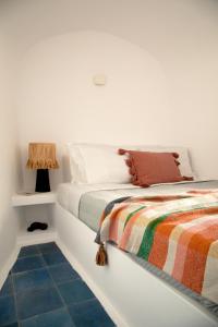 a white bedroom with a bed and a side table at Amphora Villas Santorini Akrotiri in Akrotiri