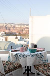 een tafel met kopjes en borden op een balkon bij Amphora Villas Santorini Akrotiri in Akrotiri