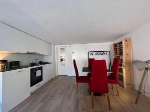 een keuken en eetkamer met rode stoelen en een tafel bij Appartement en vieille ville de Porrentruy in Porrentruy