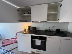 een keuken met witte kasten en een zwarte oven bij Appartement en vieille ville de Porrentruy in Porrentruy