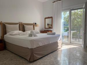 1 dormitorio con cama grande y ventana grande en Petra Mare Apartments, en Alyki
