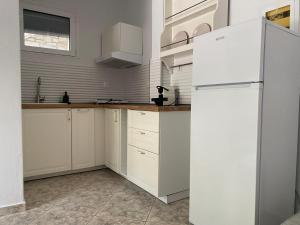 a kitchen with white cabinets and a white refrigerator at Petra Mare Apartments in Alyki