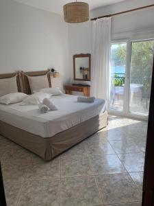 1 dormitorio con cama y ventana grande en Petra Mare Apartments, en Alyki