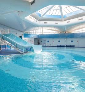 a large swimming pool with a slide in a building at Rockley Park, Gorse Hill 38 in Lytchett Minster