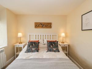 a bedroom with a white bed with two lamps at Wharf Cottage in Lechlade