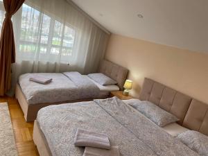 1 dormitorio con 2 camas y ventana en Apartment Perla en Pristina