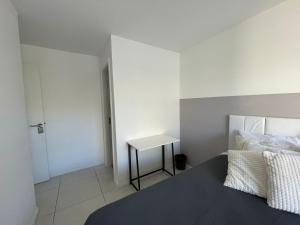 a white bedroom with a bed and a table at Mediterrâneo 507 - Todo Equipado, Ar Condicionado, Churrasqueira na Varanda, Internet Fibra 600MB, Estacionamento Grátis in Cabo Frio