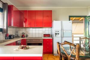 a kitchen with red cabinets and a white refrigerator at Villa Koutoupakia in Ratzaklíon