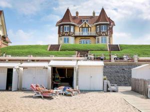 people laying in chairs on the beach in front of a house at Apartment on Belgian Coast with Sea View in De Haan