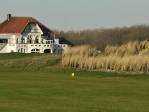 een groot wit huis met een gele bal in het gras bij Bries 0202 apartment with a sunny terrace in De Haan