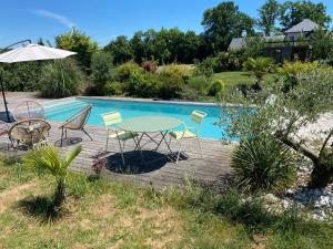 eine Terrasse mit einem Tisch und Stühlen neben einem Pool in der Unterkunft Villa contemporaine avec piscine sur 4000 m2 à Rodez 9 personnes in Onet le Château