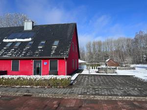 ein rotes Haus mit schwarzem Dach im Schnee in der Unterkunft Rieke - a74221 in Malchow