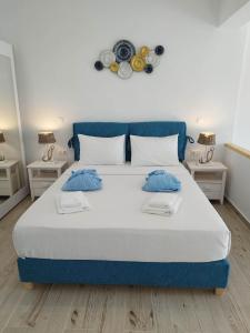 a blue and white bed in a room with two tables at ILIOPOULOS Apartments in Mourteri
