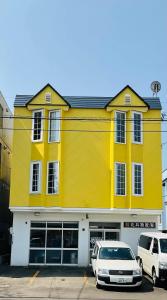 a yellow building with two cars parked in front of it at Warm House3 in Sapporo