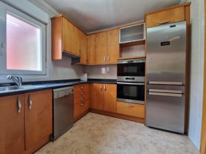 une cuisine avec des placards en bois et des appareils en acier inoxydable dans l'établissement Family Apartment / Apartamento familiar Getxo, à Getxo