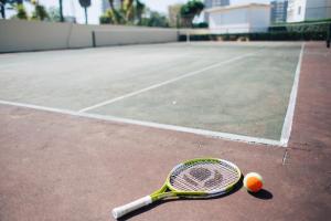 a tennis racket and a tennis ball on a tennis court at Dunas do Alvor - Torralvor in Alvor