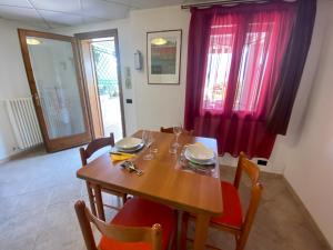 a dining room with a wooden table and red curtains at Riky Apartment Panoramic View in Consiglio di Rumo