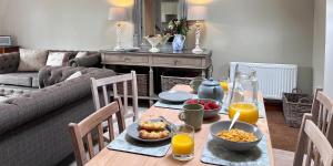 a dining room table with food and orange juice on it at Campden Place - 2 Bed Home in Central Chipping Campden in Chipping Campden