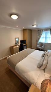 a bedroom with a large white bed with a desk and a chair at Horseshoes cafe and lodge in Welbourn