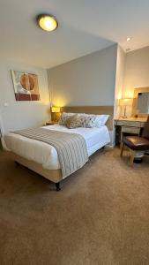 a bedroom with a large bed with a desk and a chair at Horseshoes cafe and lodge in Welbourn