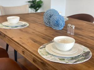 a wooden table with two bowls and plates on it at Luxury house in heart of Hopeisland in Gold Coast