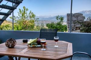un tavolo in legno con 2 bicchieri di vino e frutta di Bella-Maria at Aptera with mountain and sea view - Ground Floor a Chania