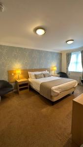 a bedroom with a bed and two lamps and a chair at Horseshoes cafe and lodge in Welbourn