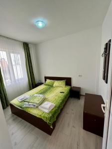 ein Schlafzimmer mit einem Bett mit einer grünen Bettdecke in der Unterkunft Vila Bordei Verde in Mamaia Nord – Năvodari