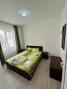 a bedroom with a bed with a green comforter at Vila Bordei Verde in Mamaia Sat/Năvodari
