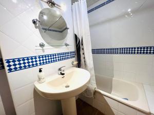 Marina 4 apartment في هويلفا: حمام مع حوض ومرآة وحوض استحمام