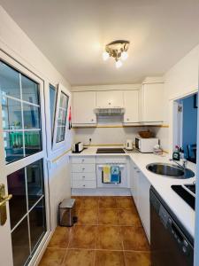 een keuken met witte kasten en een wastafel bij Marina 4 apartment in Huelva