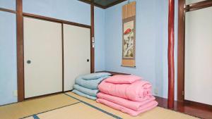 a pile of blankets sitting on the floor in a room at ゲストハウス 編湊 in Nakaminato