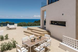 a patio with a table and chairs and the ocean at Ventus Villa - A Luxury Sea View Retreat in Akrotiri in Akrotiri