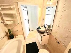 a bathroom with a tub and a sink and a toilet at Sea Promenade Luxury Apartment in Świnoujście