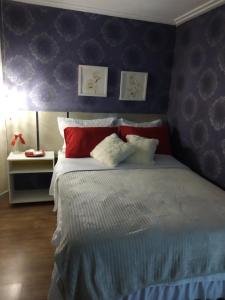 um quarto com uma cama com almofadas vermelhas e brancas em Gastaldon Suite em Chapecó