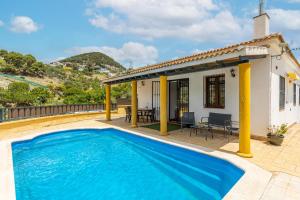 a villa with a swimming pool in front of a house at Villa 4 Vientos in Málaga