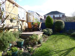 a backyard with a wooden deck with a table and chairs at Whitstable house with a view and 2 parking spaces in Kent