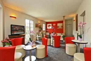 a waiting room with red and white chairs and tables at Hostellerie du Causse in Gramat
