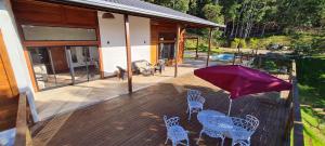 a patio with chairs and an umbrella on a deck at Linda Casa de Campo com Piscina na Rota dos Ipês in Domingos Martins