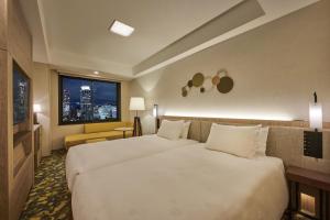 神戸市にあるザ ロイヤルパーク キャンバス 神戸三宮のベッド2台と窓が備わるホテルルームです。